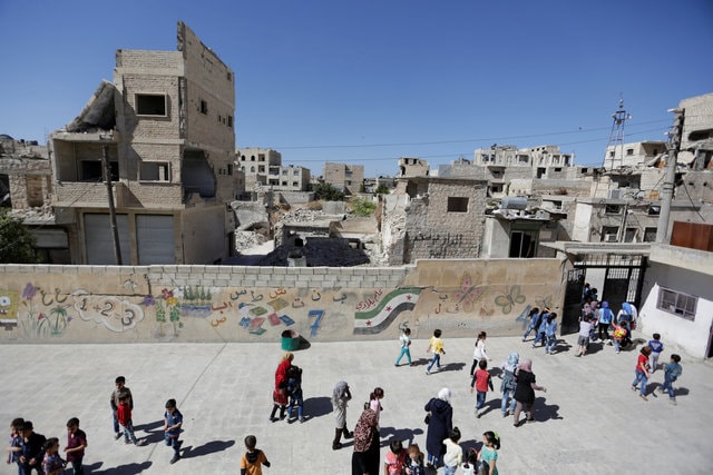 Children finish their first day of school in the rebel held town of Maaret al-Numan, Syria September 24, 2016. The text on the wall next to the Free Syrian Army flag reads in Arabic, "My country's flag." (Photo: Syria)