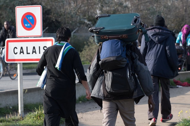 A migrant carries bags with his belongings as he walks past the Calais city limit sign in Calais, France, October 25, 2016. (Photo: Reuters)