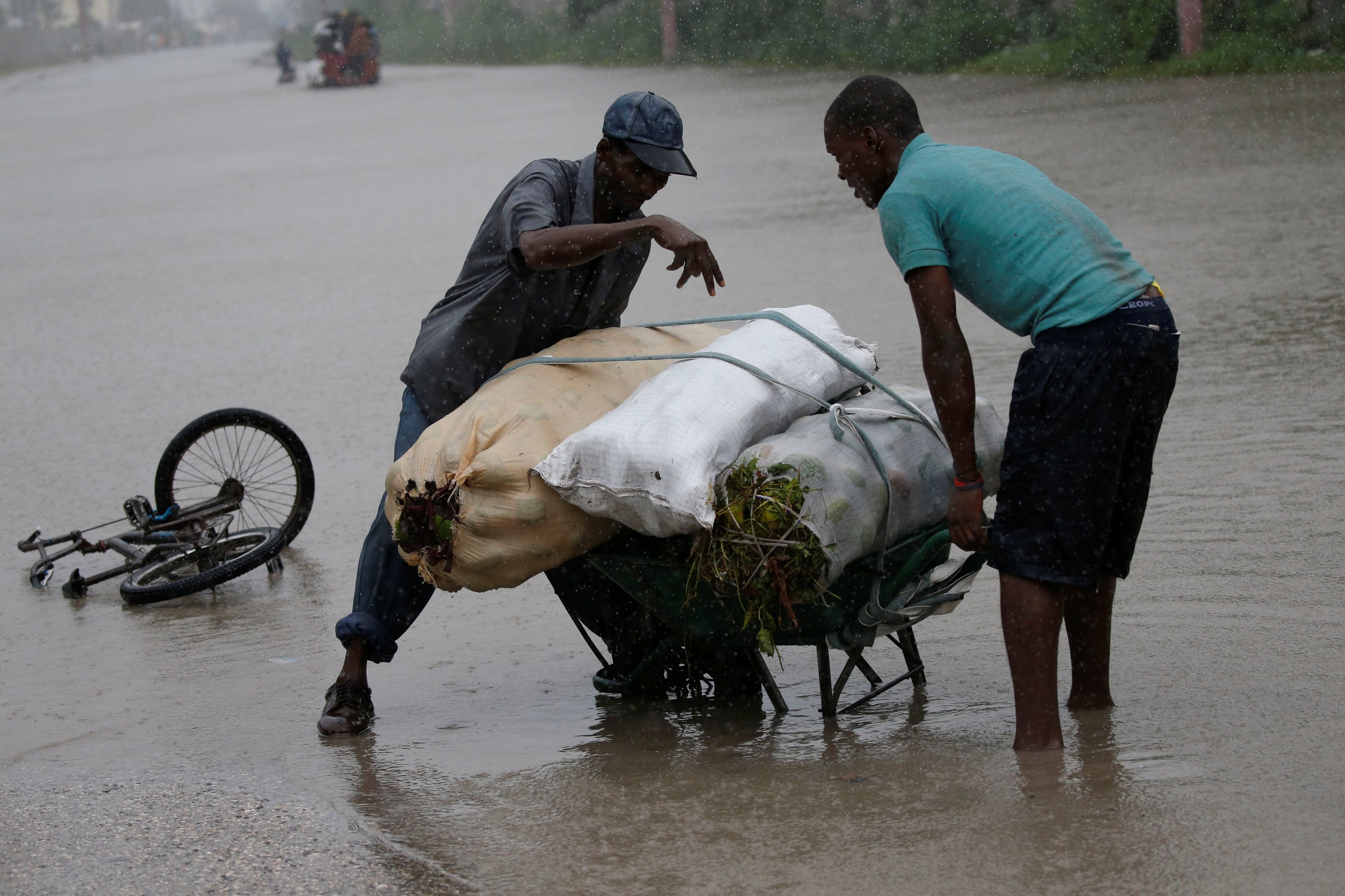 Men attempt to push a wheelbarrow across a flooded street while Hurricane Matthew passes through Port-au-Prince, Haiti, October 4, 2016. (Photo: Reuters)