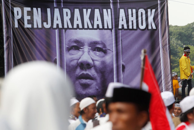 Members of hardline Muslim groups stand around a poster which reads "Ahok should be jailed". (Photo: Reuters)