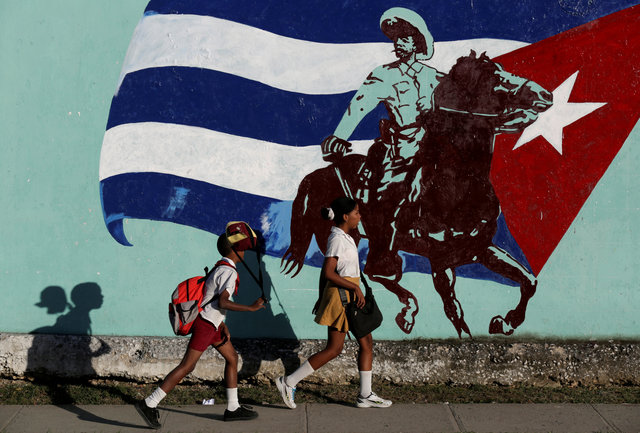 Cuban students walk in front of a mural of the Cuban flag in Havana, Cuba, November 22, 2016. (Photo: Reuters)