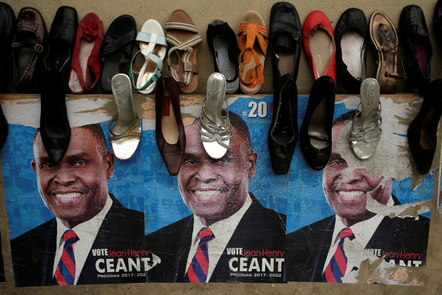 Posters of presidential candidate Jean-Henry Ceant, of Renmen Haiti (Love Haiti) Party, are seen on a wall behind shoes on display for sale in a street of Port-au-Prince, Haiti. (Photo: Reuters)