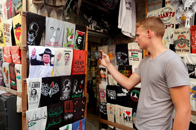 A man photographs T-shirts bearing images of newly elected US President Donald Trump (L) next to one with an image of US President Barack Obama, displayed outside a stall in Jerusalem's Old City November 9, 2016. (Photo: Reuters)