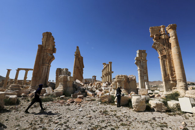 Journalists walk near the remains of the Monumental Arch in the historical city of Palmyra, in Homs Governorate, Syria. (Photo: Reuters/ File Photo)