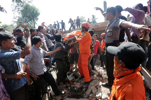 Rescue workers and police remove a victim from a collapsed building (Photo: Antara Foto/ Irwansyah Putra via Reuters)