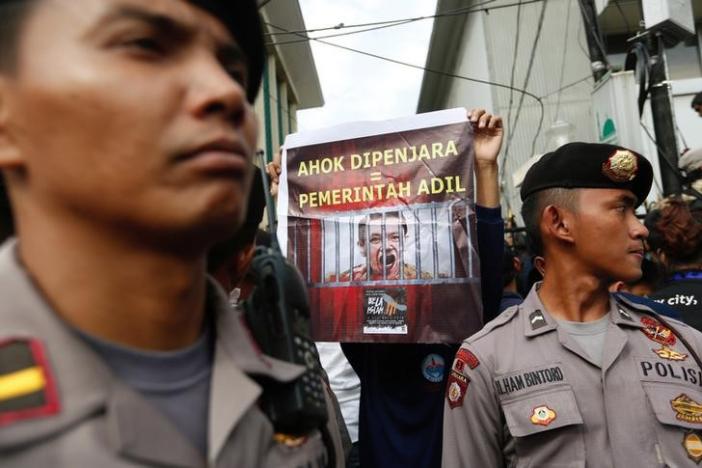 A protester holds a banner outside a court during the first day of the blasphamy trial of Jakarta's Governor Basuki Tjahaja Purnama, also known as Ahok, in Jakarta, Indonesia  (Photo:  Reuters)