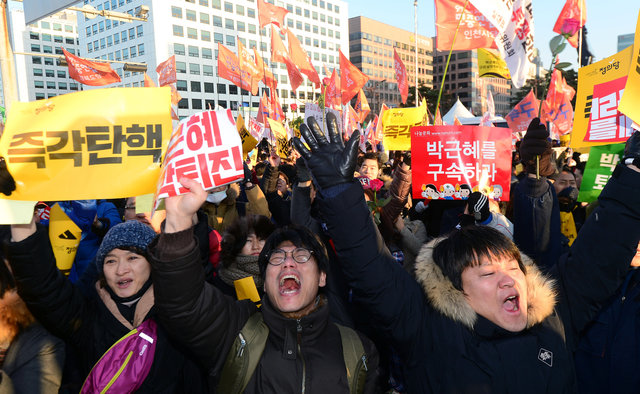 People react after impeachment vote on South Korean President Park Geun-hye was passed, in front of the National Assembly in Seoul, South Korea, December 9, 2016. The sign reads "Step Down Park Geun-hye". (Photo: News1 via Reuters)
