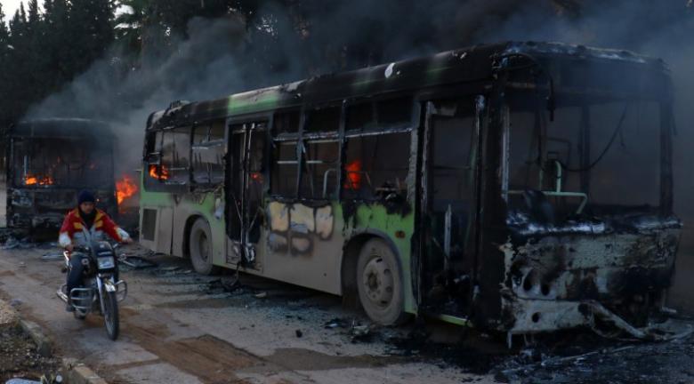 A man on a motorcycle drives past burning buses while en route to evacuate ill and injured people from the besieged Syrian villages of al-Foua and Kefraya, after they were attacked and burned, in Idlib province, Syria. (Photo: Reuters)